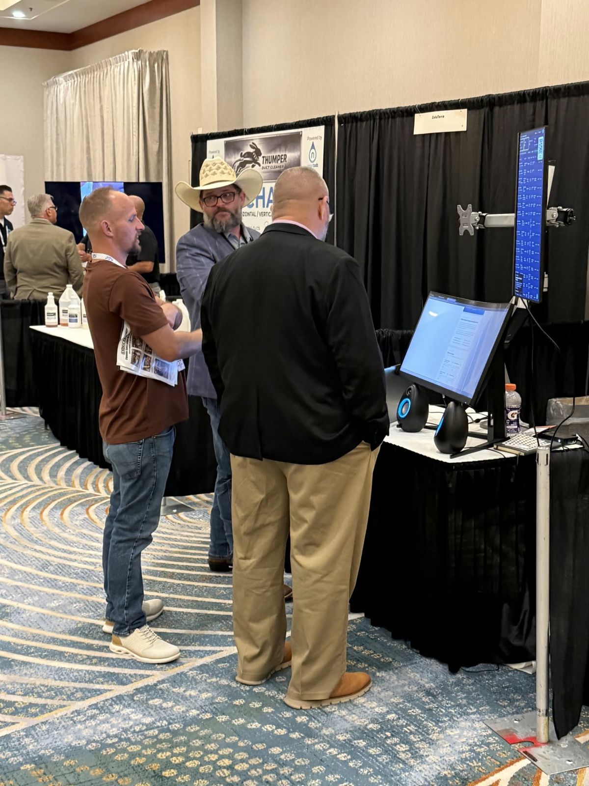 Three visitors in conversation at the Liftori booth