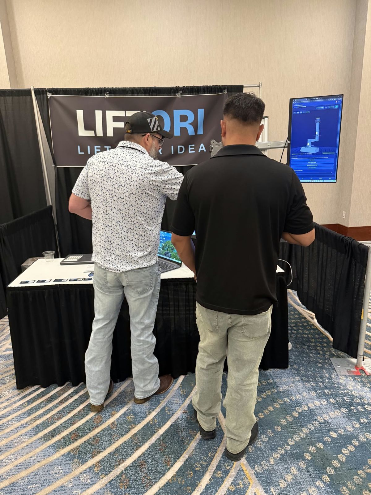Visitors at the Liftori booth looking at the Duct Designer on a tall screen