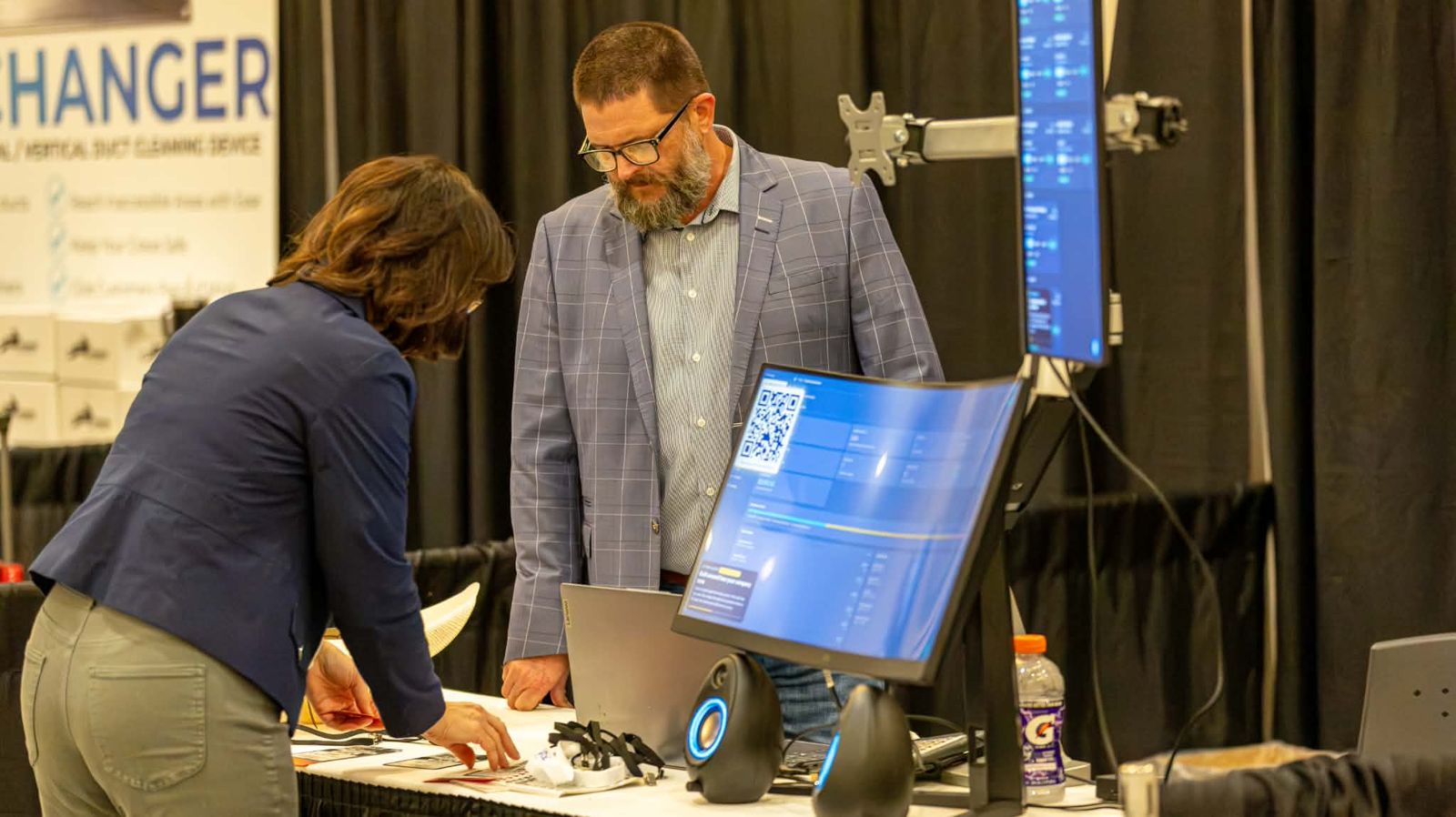 Walking a visitor through the Liftori Hoods Command Center at the booth
